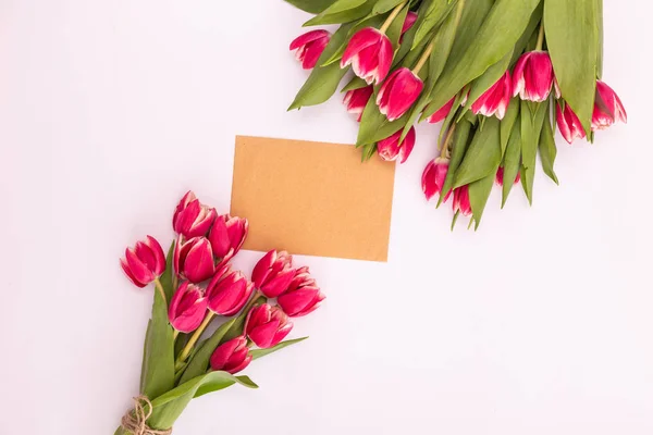 A bouquet of beautiful tulips and a card for text on a white background fork on top. Mother\'s day background, International Women\'s Day, birthday. Holiday, give.
