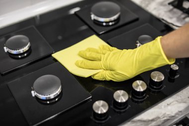 Bir cam seramik Ocak mutfakta bir sarı mikrofiber bezle bir kadın el losyonları.