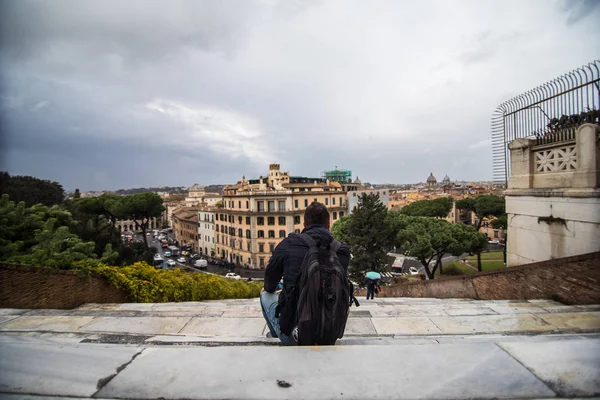 Мужчина смотрит на вид на город сидя на монументальной лестнице базилики Санта-Мария в Ара-Коэли в Риме, Италия — стоковое фото