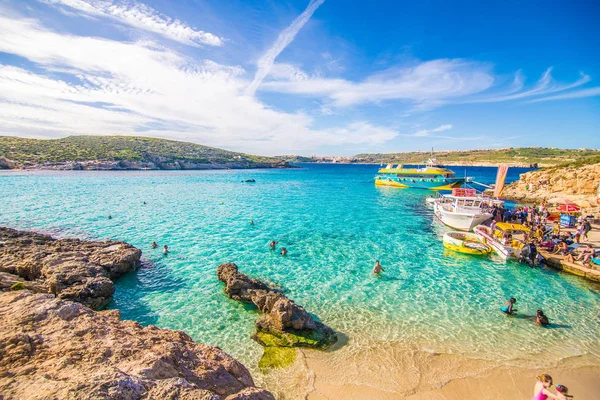 Comino, Malta - Noviembre, 2018: Turistas se congregan en Blue Lagoon para disfrutar del agua turquesa en un día soleado de verano con cielo azul claro y barcos en la isla de Comino, Malta . — Foto de Stock