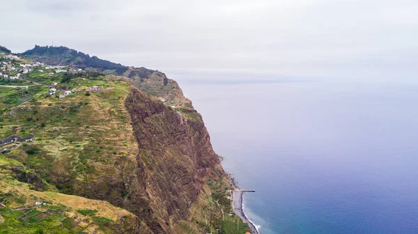 Aerial panoramic cityscape view of the cities in madeira with houses in front and covered mountains and white clouds — Stock Photo, Image