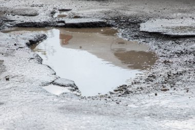 yol çukurları ve kar üzerinden su birikintileri çatlaklar ile kaplıdır. Yatay gri bulutlu havalarda kış yolun. Yol onarım kavramı, arabanın sürücüsü için opaklık