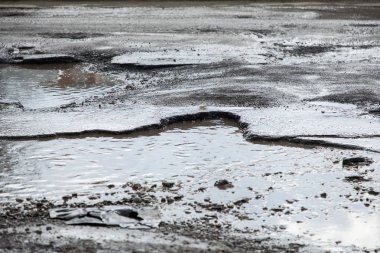 yol çukurları ve kar üzerinden su birikintileri çatlaklar ile kaplıdır. Yatay gri bulutlu havalarda kış yolun. Yol onarım kavramı, arabanın sürücüsü için opaklık