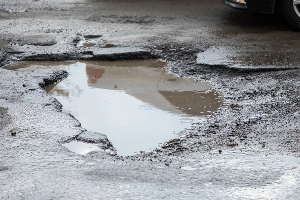 Buraco no pavimento significando infra-estrutura defeituosa. Pathole na estrada . — Fotografia de Stock