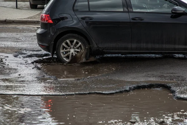 Pojazd uderzając pothole w mieście ulica rozpryskiwania błotnistej wody. — Zdjęcie stockowe