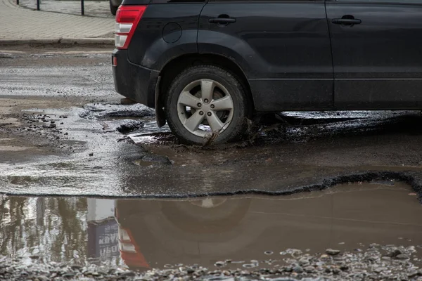 Pneu de carro prestes a passar por um grande buraco cheio de água — Fotografia de Stock