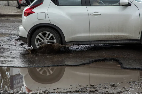Pneu de carro prestes a passar por um grande buraco cheio de água — Fotografia de Stock