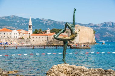Budva, Karadağ - Temmuz 2019: Dansçı Kız Heykeli - Eski Budva kentinin arka planında turistler için çekici bir heykel ve popüler bir fotoğraf fırsatı.