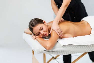 Genç bir kadın güzellik salonunda sırt masajı yaptırıyor..