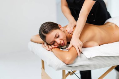 Genç bir kadın güzellik salonunda sırt masajı yaptırıyor..