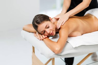 Genç bir kadın güzellik salonunda sırt masajı yaptırıyor..