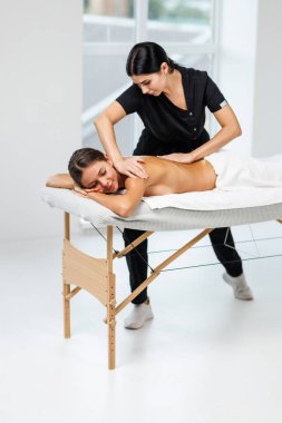 Genç bayan masajcı müşterisine masaj yapıyor.