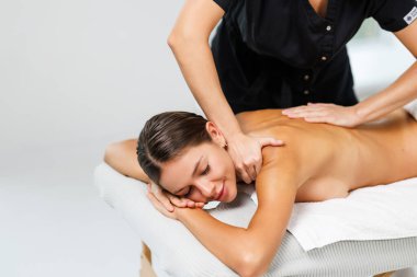 Kaplıca salonunda sırt masajı yaptıran genç bir kadın. Güzellik tedavi konsepti.