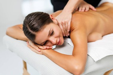 Spa terapisi. Salondaki masaj sırasında masada uzanan güzel genç bir kadın.