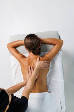 Güzel bir kadın, beyaza sırt masajı yapıyor, yukarıdan bakıyor. Genç bayan, kaplıcadaki kadın terapistten tam vücut masajı yaptırıyor..