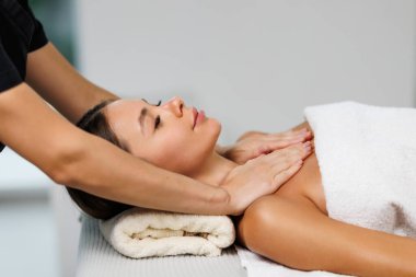 Kadın yüzüne masaj yapan masözlerin ellerini kapatın. Kadın zevkle gözlerini kapadı.