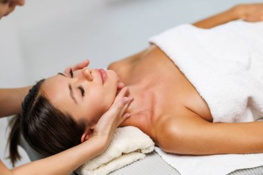 Kaplıcada yüz masajı yaparken kadın terapistin elleri rahat kadının çenesini ve boynunu ovuyor. Bin yıllık kadının iyileştirme akupunktur prosedürünü yüksek açılı görmesi