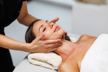 Kaplıcada yüz masajı yaparken kadın terapistin elleri rahat kadının çenesini ve boynunu ovuyor. Bin yıllık kadının iyileştirme akupunktur prosedürünü yüksek açılı görmesi