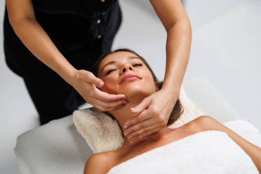 Yüz masajı. Kapalı gözlü güzel bir kadın yüz masajı sırasında spa merkezinde rahatlıyor. Güzellik salonunun müşterisinin masöz yüzü. Cilt bakımı, spa, tedavi ve yüz masajı kavramı.