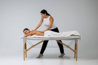 Genç bayan masajcı müşterisine masaj yapıyor.