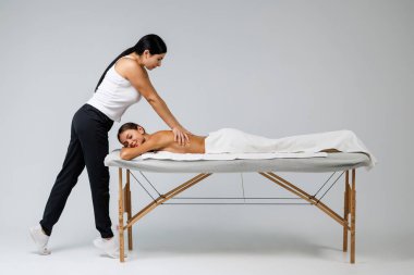 Genç bayan masajcı müşterisine masaj yapıyor.