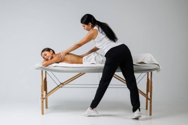 Çalışkan kadın masaj terapisti spa kompleksindeki rahatlatıcı kadına masaj yapıyor.