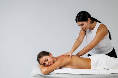 Masaj terapisti sırtına masaj yaparken rahat kadın, kadın kaslarında gerginliği azaltmak için baskı uyguluyor.