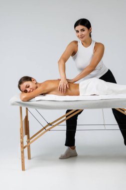 Çalışkan kadın masaj terapisti spa kompleksindeki rahatlatıcı kadına masaj yapıyor.