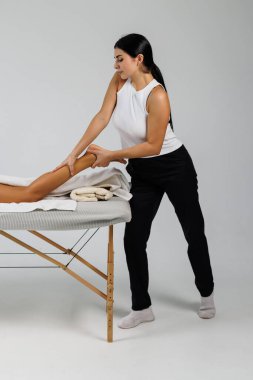 Osteopat, tedavi odasında hastanın bacağına masaj yapıyor.