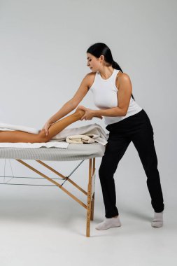 Osteopat, tedavi odasında hastanın bacağına masaj yapıyor.