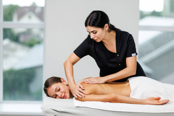 Spa therapy. Beautiful young woman lying on table during massage in salon, closeup