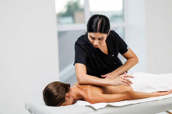 Woman receiving back massage with oil in spa salon, closeup