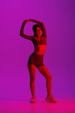 Esniyorum. Genç sportif kadın eğitimi neon ışıklarıyla izole edilmiş. Atletik ve zarif. Modern spor, aksiyon, hareket, gençlik konsepti. Güzel beyaz kadın pratik yapıyor.