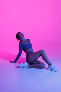 Fantezi gibi havalı bir kadının baskılı vücut giysisi giymiş fotoğrafı dizlerine otur ve soyulmuş plastik menekşe renginin tadını çıkar.