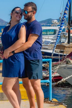 Pachi, Megara, Yunanistan limanında birlikte duran çift. Yat, yelkenli ve mavi sularla romantik bir şekilde kucaklaşıp yaz için bir zemin oluştururlar..