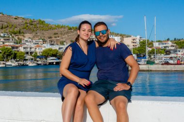 Pachi, Megara, Yunanistan limanında dinlenen bir çift. Yat, tekne ve kıyı kasabasıyla birlikte deniz kenarında oturup manzaralı bir fon oluşturuyorlar..