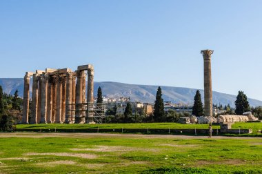 Yunanistan 'ın Atina kentindeki antik Olympieion Tapınağı, Korint sütunları, yıkılmış kalıntıları ve şehrin ve etrafındaki dağların manzaralı manzaralarıyla,.