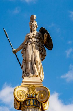Atina Akademisi 'ndeki İyonik sütunun tepesinde duran tanrıça Athena' nın mermer heykeli, Atina, Yunanistan 'da mavi gökyüzünün altında fotoğraflandı.