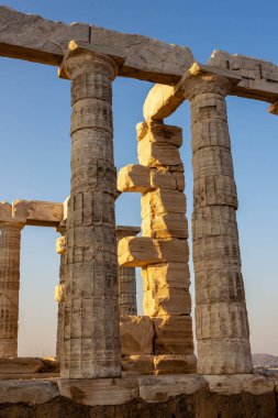 Yunanistan 'ın Attica kentindeki Poseidon Tapınağı' nın Antik Dorik sütunları, sıcak günbatımı ışığı ile aydınlatılmış mermerle ayrıntılı olarak ele geçirildi.