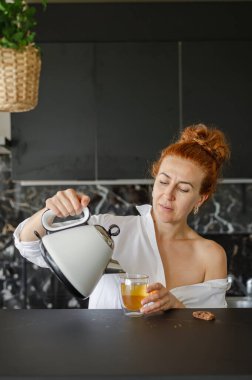 Rahatlamış bir kadın sıcak bir çay ve tatlı bir kurabiyenin tadını çıkarıyor..