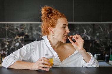 Rahatlamış bir kadın sıcak bir çay ve tatlı bir kurabiyenin tadını çıkarıyor..