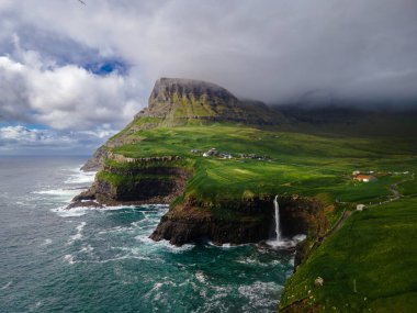 Dramatik Mulafossur şelalesi Gasadalur köyü ve arka planda kayalıklarla okyanusa dökülüyor..
