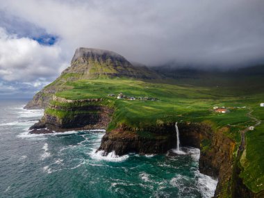 Dramatik Mulafossur şelalesi Gasadalur köyü ve arka planda kayalıklarla okyanusa dökülüyor..
