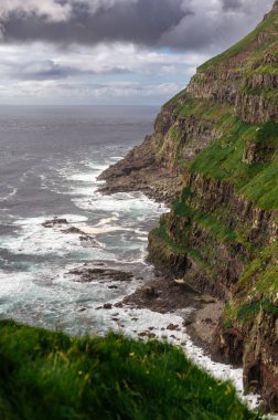 Dramatik Mulafossur şelalesi Gasadalur köyü ve arka planda kayalıklarla okyanusa dökülüyor..