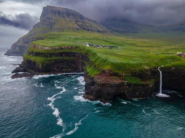 Dramatik Mulafossur şelalesi Gasadalur köyü ve arka planda kayalıklarla okyanusa dökülüyor..