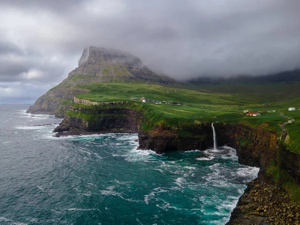 Dramatik Mulafossur şelalesi Gasadalur köyü ve arka planda kayalıklarla okyanusa dökülüyor..