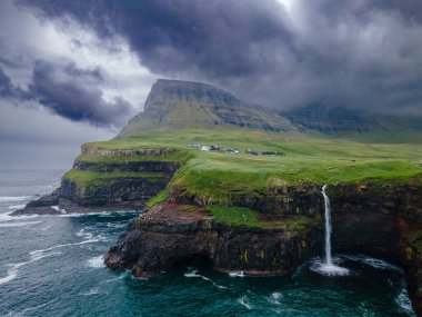 Dramatik Mulafossur şelalesi Gasadalur köyü ve arka planda kayalıklarla okyanusa dökülüyor..