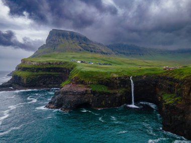 Dramatik Mulafossur şelalesi Gasadalur köyü ve arka planda kayalıklarla okyanusa dökülüyor..