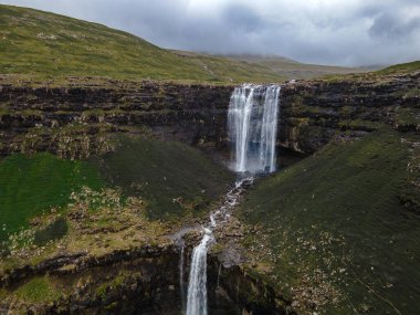 Muhteşem Fossa şelalesi, Faroe Adaları 'nın en yüksek şelalesi, Kuzey Atlantik' in engebeli kayalıklarından aşağı dökülüyor..