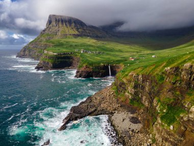 Dramatik Mulafossur şelalesi Gasadalur köyü ve arka planda kayalıklarla okyanusa dökülüyor..